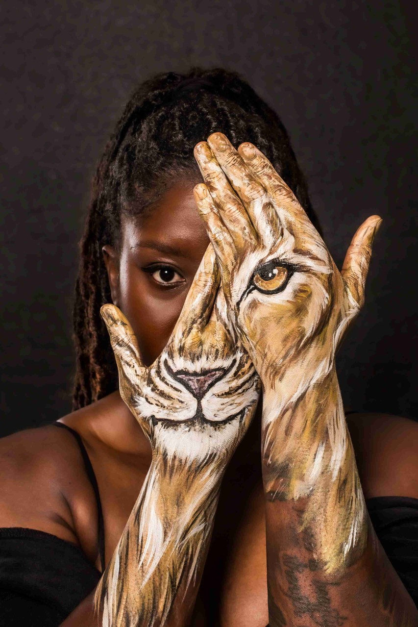 Anita Asante with lioness hand painting covering her face.